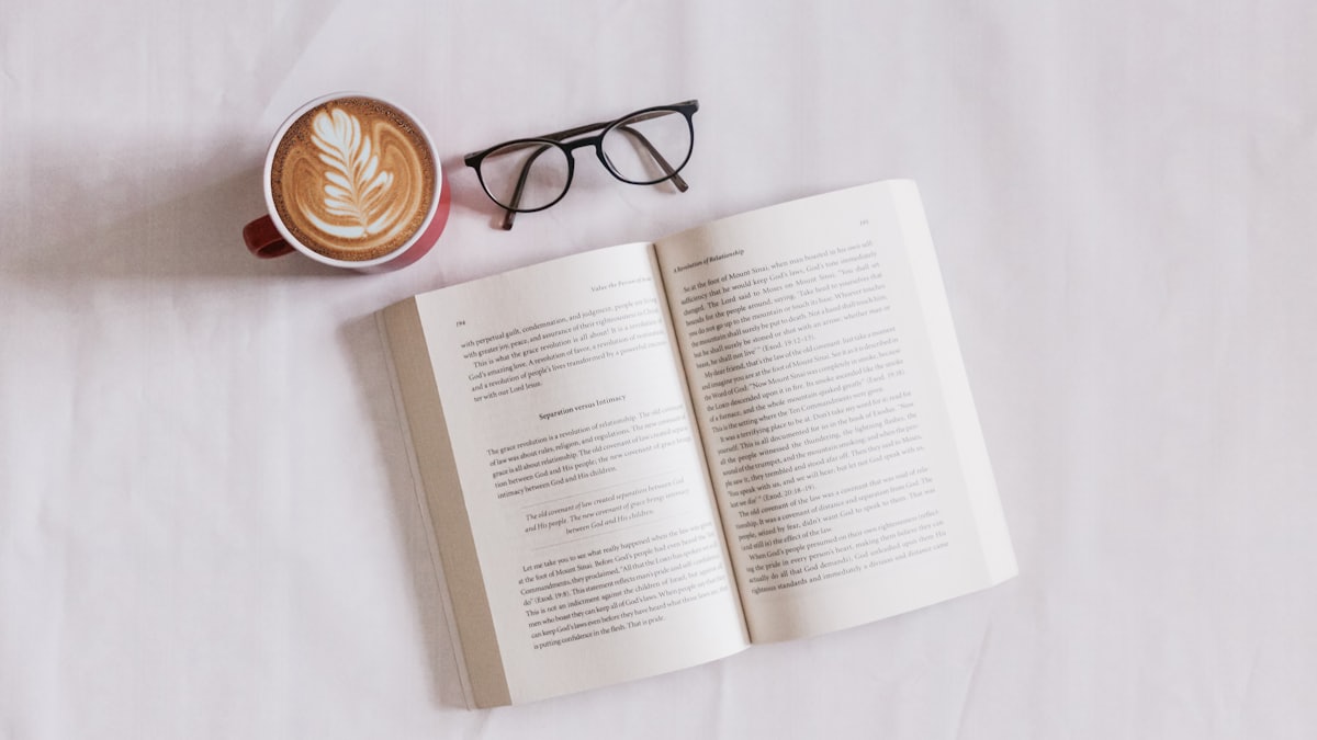 Livre ouvert à côté d'un café et de lunettes, symbole de la lecture rapide en préparation au TCF Canada